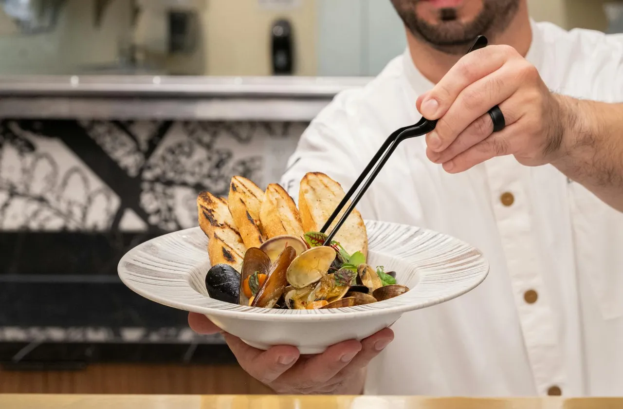 A chef plating mussels and grilled bread at Frolik